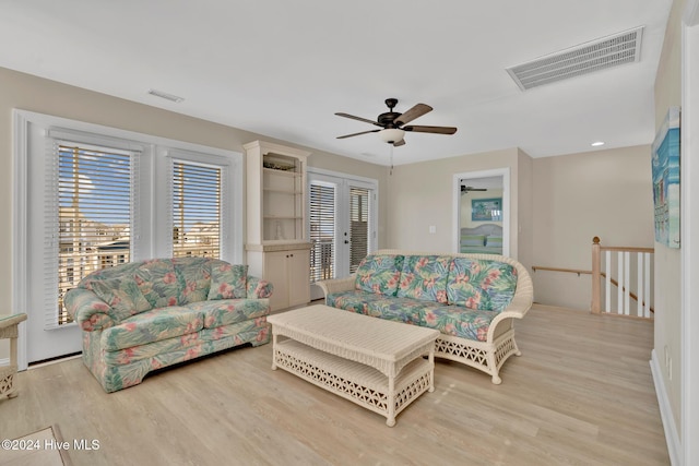 living room with a wealth of natural light, light wood-type flooring, and french doors