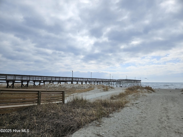 view of dock with a water view and a beach view