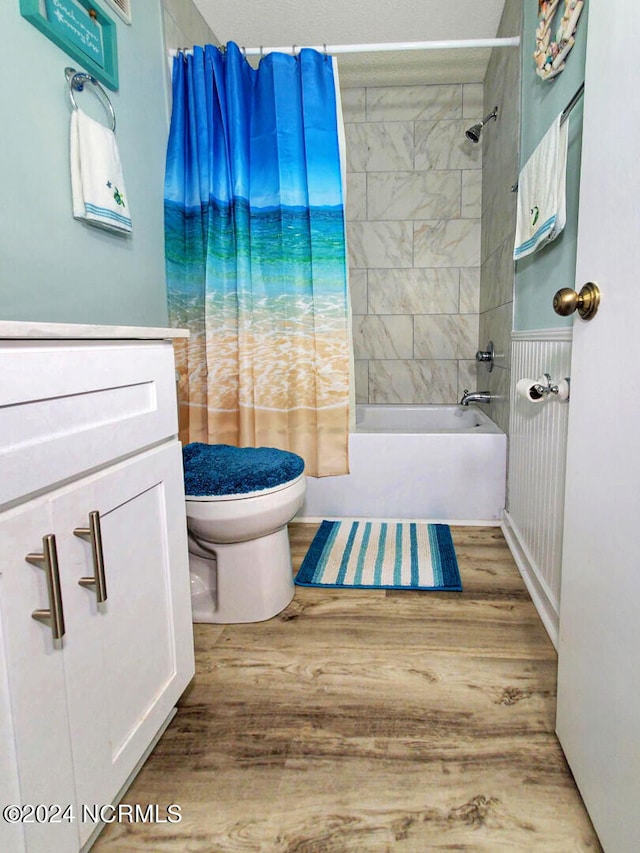 full bathroom with hardwood / wood-style floors, vanity, shower / tub combo with curtain, and toilet