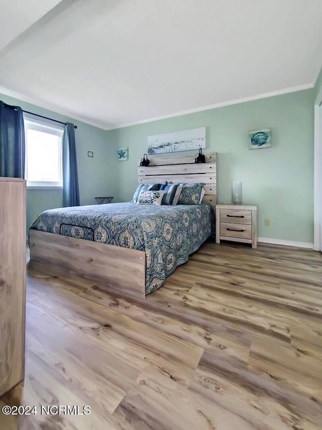 bedroom featuring light wood-type flooring and crown molding