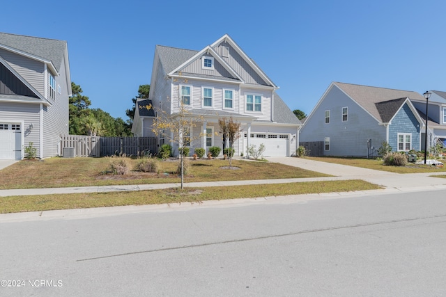 view of front of property with a front yard, central AC unit, and a garage