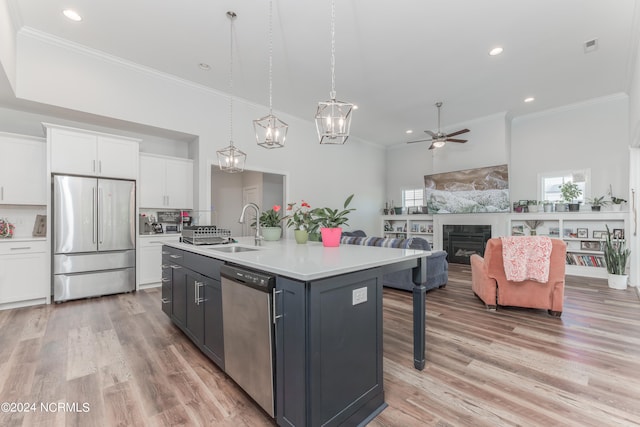 kitchen with a kitchen island with sink, white cabinets, decorative light fixtures, appliances with stainless steel finishes, and light hardwood / wood-style floors