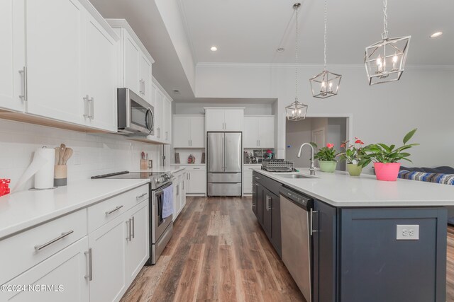 kitchen with appliances with stainless steel finishes, white cabinetry, pendant lighting, and an island with sink