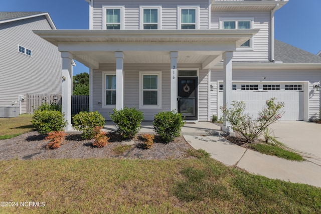 view of front of home featuring a porch, a front lawn, central AC, and a garage