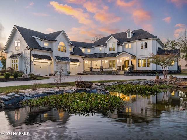 back house at dusk featuring a garage and a water view