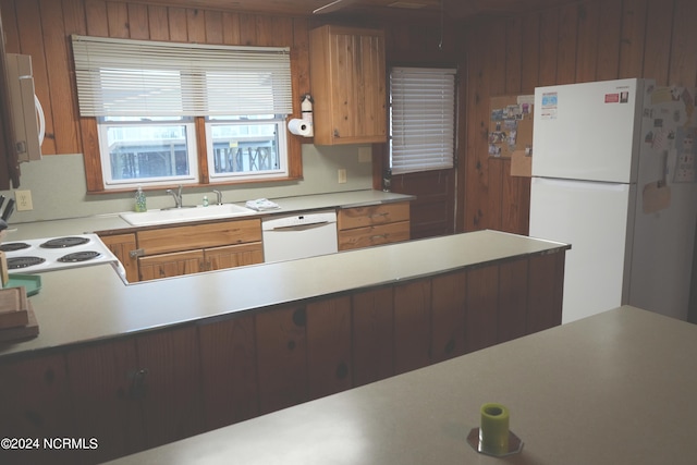 kitchen featuring wood walls, white appliances, and sink