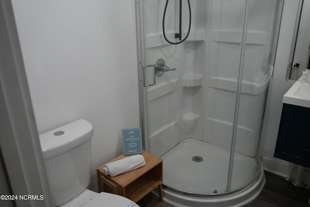 bathroom featuring hardwood / wood-style floors, vanity, a shower with door, and toilet