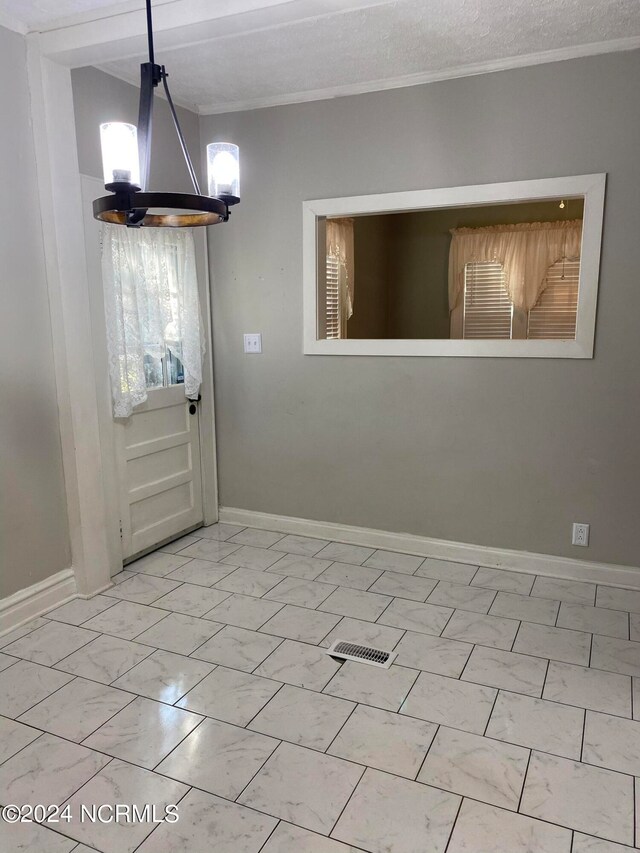 unfurnished dining area featuring an inviting chandelier and a textured ceiling