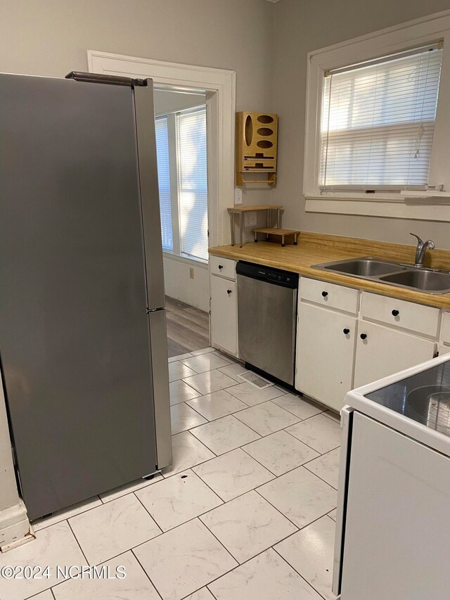 kitchen featuring plenty of natural light, white cabinets, appliances with stainless steel finishes, and sink