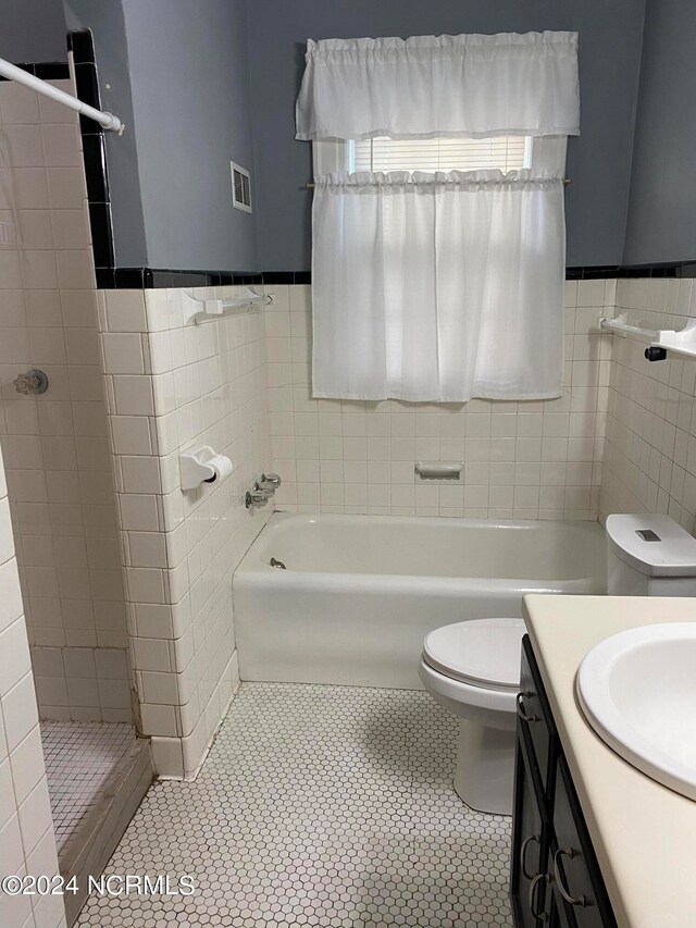 full bathroom featuring tile patterned flooring, vanity, tile walls, and toilet