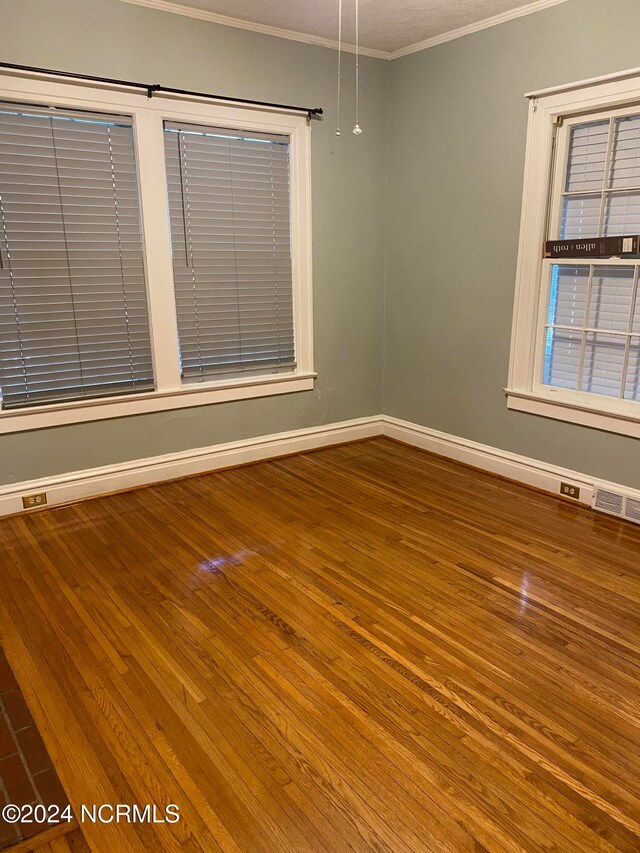 empty room with wood-type flooring and crown molding