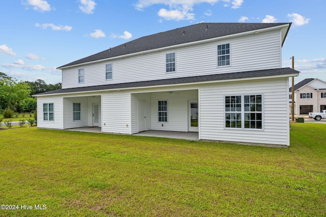 rear view of property with a yard, ceiling fan, a shingled roof, and a patio