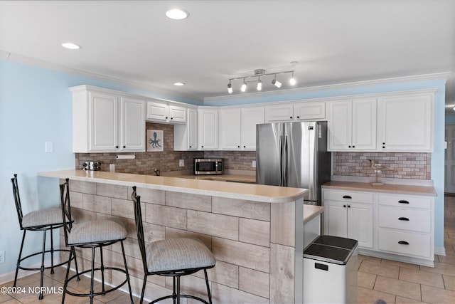 kitchen featuring appliances with stainless steel finishes, white cabinetry, and a breakfast bar area