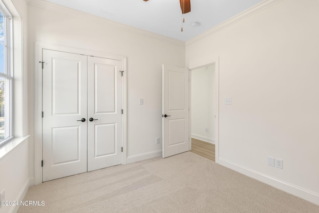 unfurnished bedroom with a closet, ornamental molding, light colored carpet, and ceiling fan