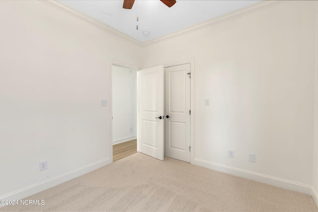 spare room with light carpet, ornamental molding, and ceiling fan