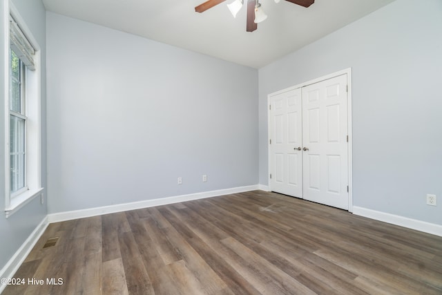 unfurnished bedroom featuring dark wood-type flooring, ceiling fan, and a closet