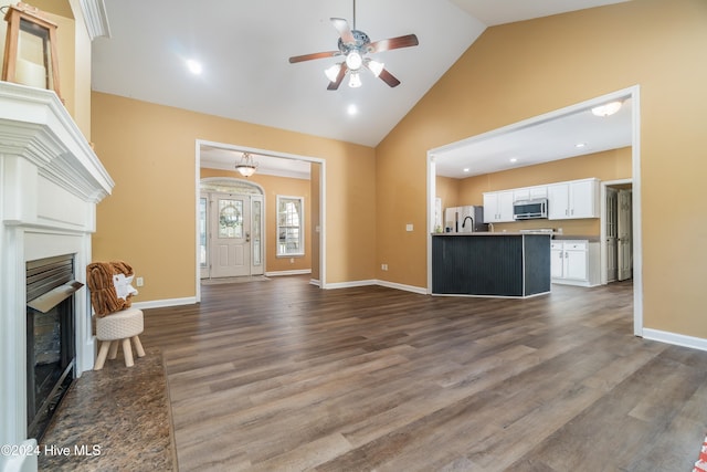 unfurnished living room with hardwood / wood-style floors, high vaulted ceiling, and ceiling fan