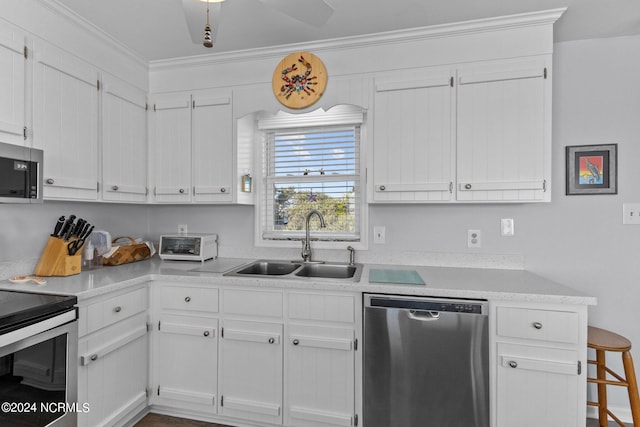 kitchen with sink, ceiling fan, stainless steel appliances, white cabinets, and ornamental molding