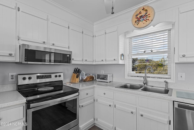 kitchen with crown molding, white cabinetry, stainless steel appliances, and sink