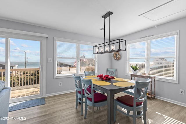 dining room with hardwood / wood-style flooring, a water view, and a wealth of natural light