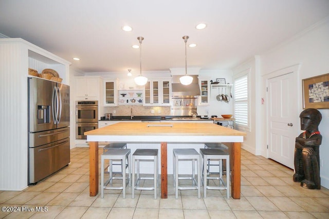 kitchen featuring appliances with stainless steel finishes, ornamental molding, tasteful backsplash, butcher block countertops, and white cabinetry