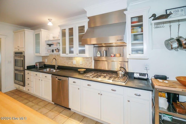 kitchen featuring appliances with stainless steel finishes, a sink, wall chimney range hood, light tile patterned floors, and tasteful backsplash