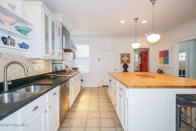 kitchen featuring butcher block countertops, a sink, appliances with stainless steel finishes, a breakfast bar area, and backsplash