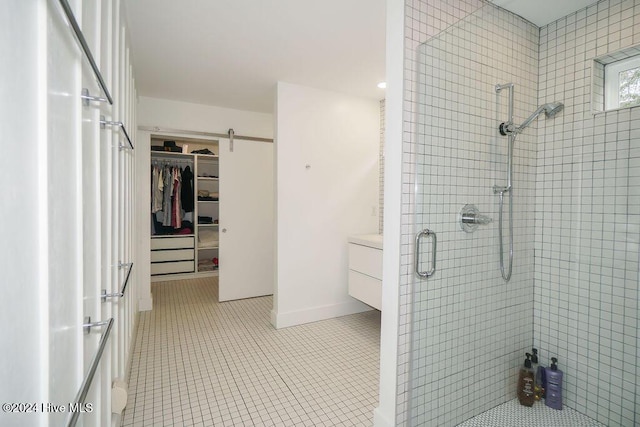 full bathroom featuring a stall shower, a walk in closet, and tile patterned flooring