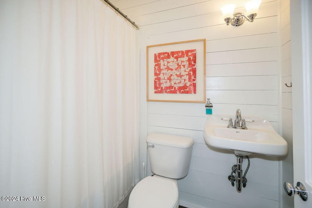 bathroom with toilet and wood walls