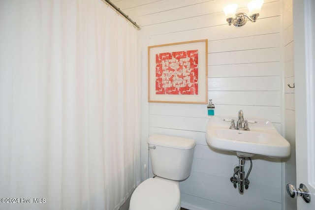 full bath with toilet, wood walls, and a shower with shower curtain