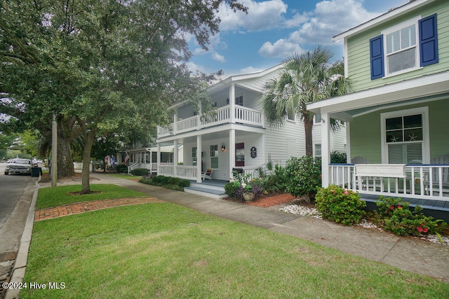 view of front of property featuring a porch, a front lawn, and a balcony