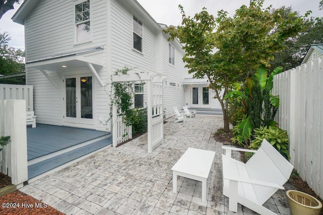 back of house with french doors, fence, a deck, and a patio area