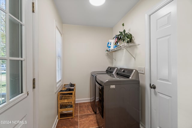 washroom with dark tile patterned flooring, plenty of natural light, and washing machine and clothes dryer