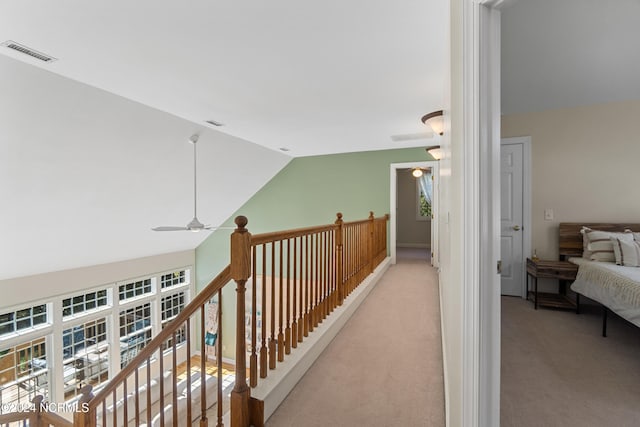 corridor with light colored carpet and vaulted ceiling