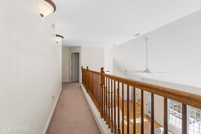 hall featuring lofted ceiling and light colored carpet