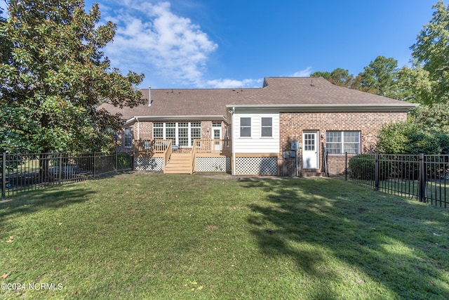 back of property with a deck and a lawn