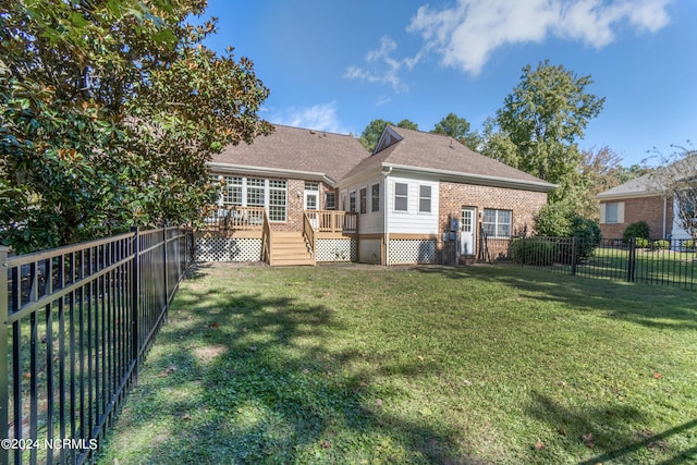 back of property with a deck and a lawn