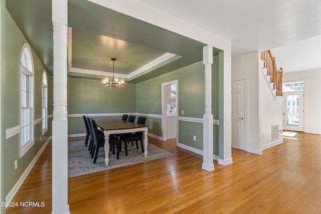 dining area featuring a chandelier, a tray ceiling, and light wood-type flooring