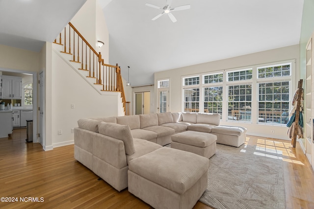 living room featuring light hardwood / wood-style flooring, high vaulted ceiling, and ceiling fan