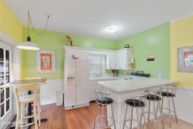 kitchen with hanging light fixtures, white cabinetry, white refrigerator with ice dispenser, and kitchen peninsula