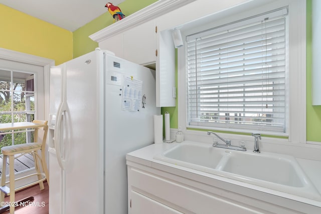 kitchen featuring a healthy amount of sunlight, white fridge with ice dispenser, hardwood / wood-style floors, and white cabinets