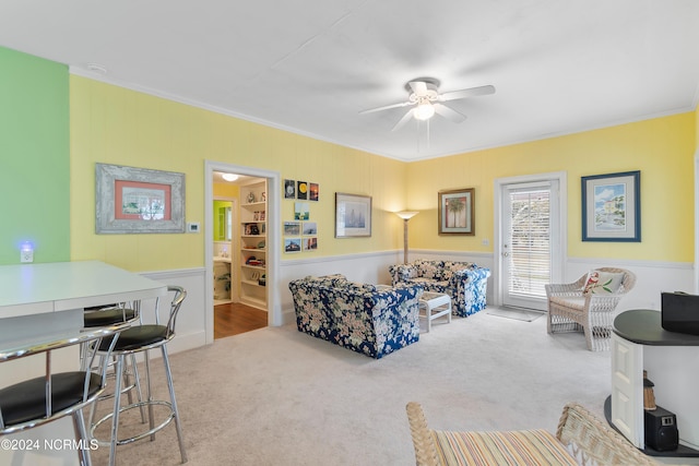 carpeted living room featuring ornamental molding and ceiling fan