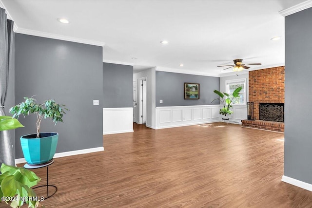 unfurnished living room with ceiling fan, a fireplace, ornamental molding, and hardwood / wood-style flooring