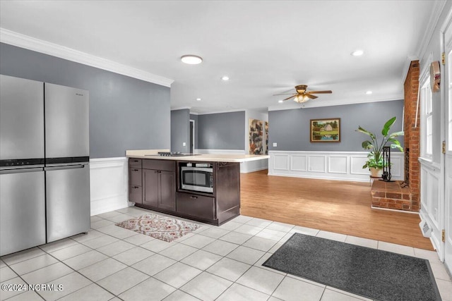 kitchen with appliances with stainless steel finishes, dark brown cabinetry, ceiling fan, crown molding, and light tile patterned floors