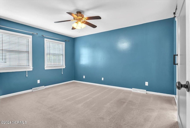 carpeted spare room featuring ceiling fan