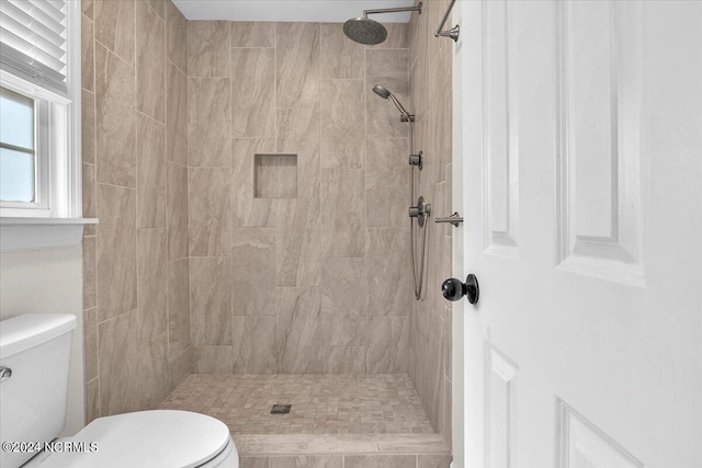 bathroom with toilet and a tile shower