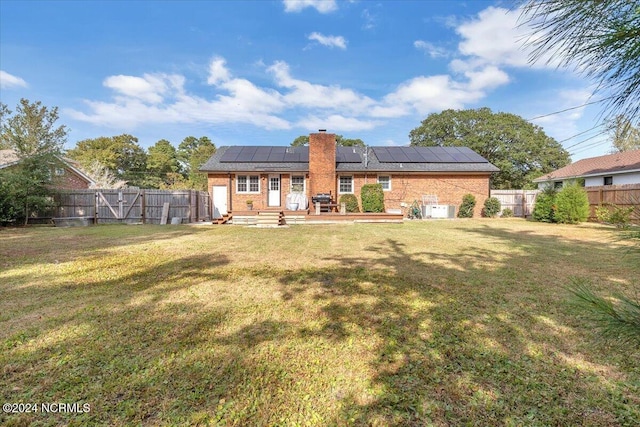 rear view of house featuring a lawn and solar panels