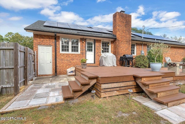 back of house with solar panels and a deck