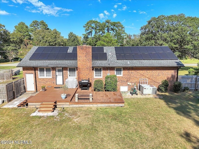 back of house featuring solar panels, a yard, a deck, and cooling unit