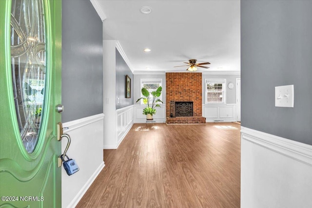 unfurnished living room featuring crown molding, ceiling fan, a fireplace, and wood-type flooring